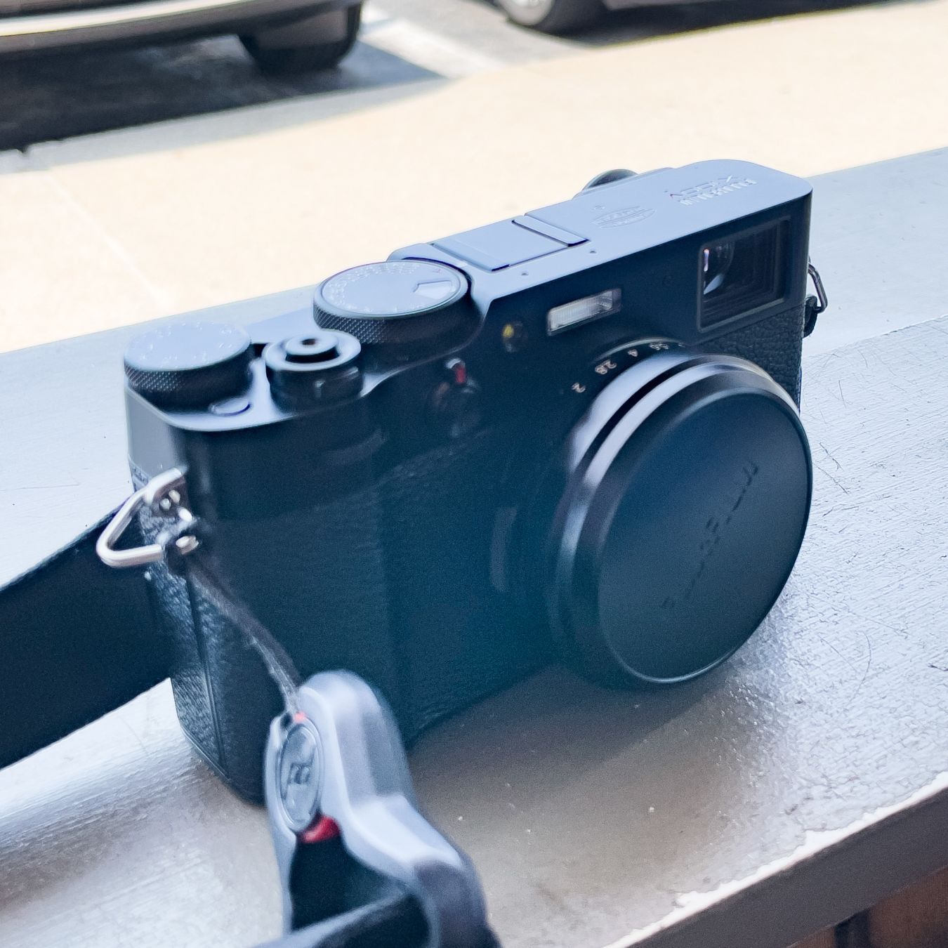 Fuji X100V camera with lens cap and strap